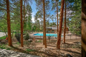 Relax by the serene pool surrounded by lush trees and a natural landscape.