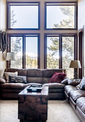 Relax in this inviting living room with a large sofa, wooden chest, and stunning mountain views.