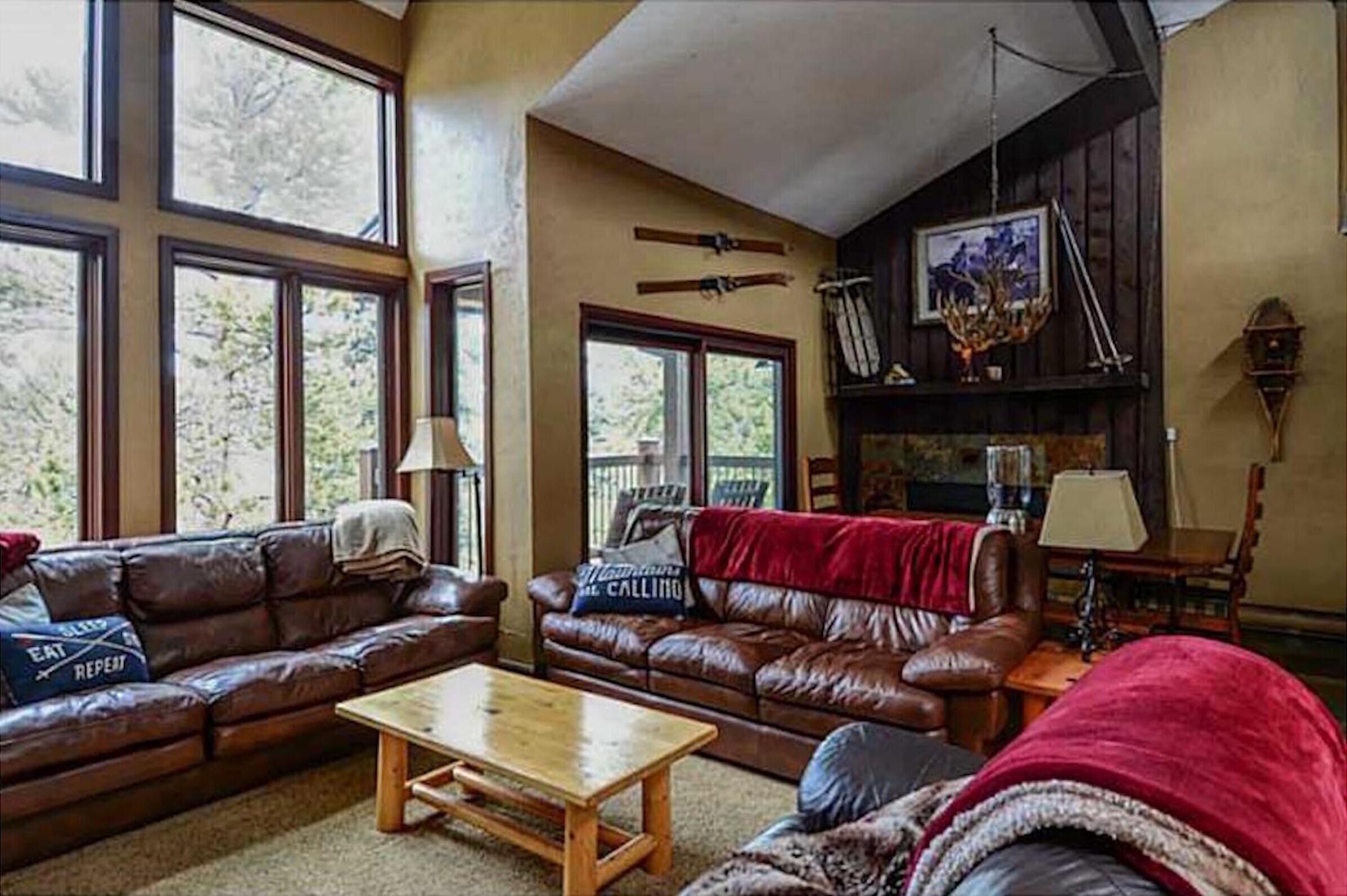 A cozy living room with leather sofas, a wooden coffee table, and a fireplace with a mantelpiece.