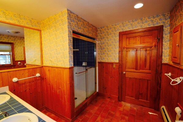 A bathroom with wooden walls, a shower, and a sink.