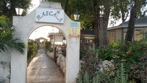Een entreeboog met de naam 'RASCALS' en een bord met openingstijden en contactgegevens.