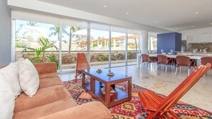 A modern hotel room with a sofa, a wooden coffee table, and a patterned rug. - Family Friendly Beachside Condo with Pool & Gym (Playa del Carmen)