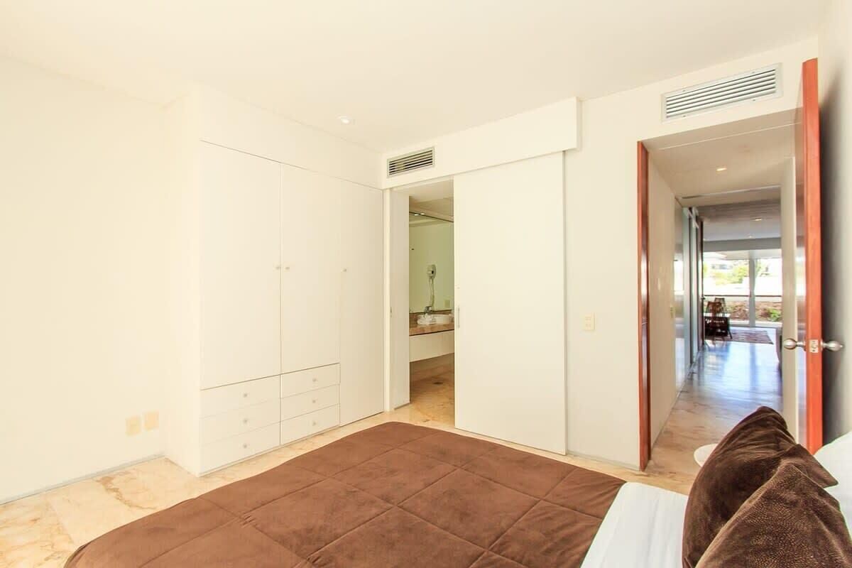 Une chambre à coucher avec un lit, une armoire et une salle de bain visible à travers une porte ouverte.