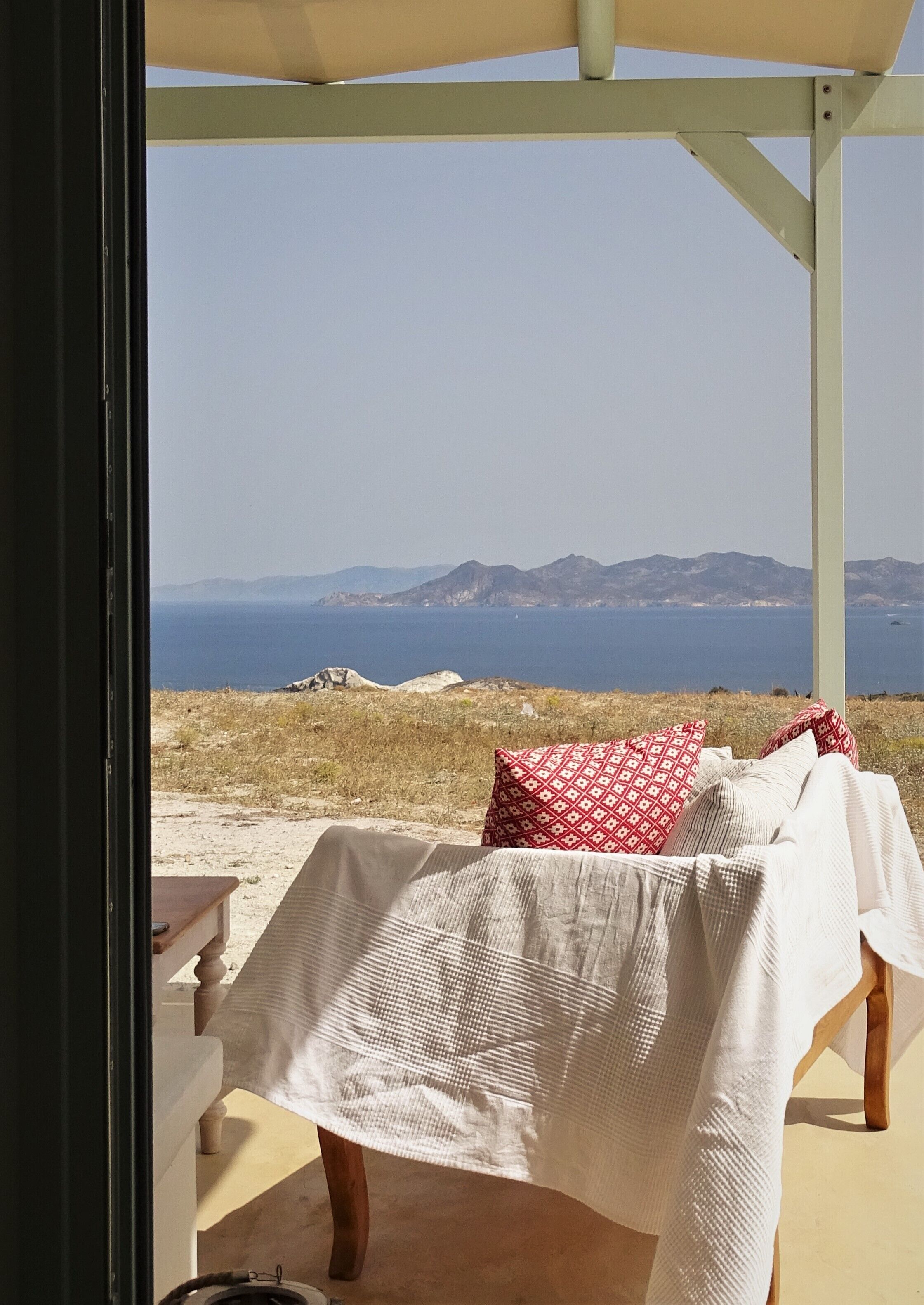 Ein überdachter Sitzbereich mit Blick auf Meer und Berge.