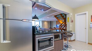 Una cocina moderna con un refrigerador de acero inoxidable, horno empotrado y estufa a gas.