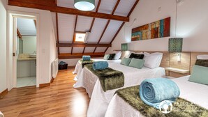 Une chambre avec deux lits, des poutres en bois, un tableau et une vue sur la cuisine.