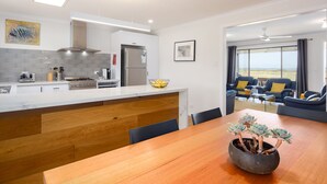 A modern kitchen with a wooden island, a dining area with a table and chairs, and a living room with a sofa and chairs.