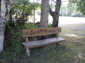 A wooden bench with a sign that reads "Wolf Ridge" in a park setting.