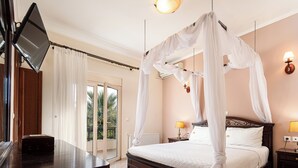 Quarto com cama de dossel, mesa de cabeceira, luminária e TV fixada na parede.