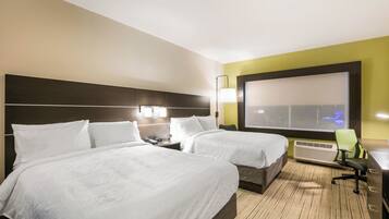 A hotel room with two beds, a desk, a chair, a TV, and a window with a view.