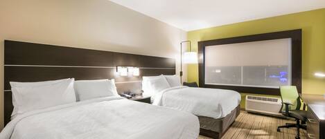 A hotel room with two beds, a desk, a chair, a TV, and a window with a view.