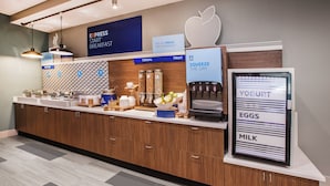 Una barra de desig amb un panell digital de menú, diferents distribuidors d'aliments i una màquina de iogurt.