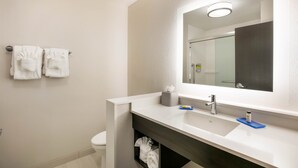 A modern bathroom with a white sink, a mirror, and two towels hanging on the wall.