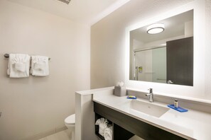 Een moderne badkamer met een witte wastafel, een spiegel en twee handdoeken aan de muur.