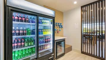 A beverage refrigerator stocked with various drinks, a small refrigerator, and a wall-mounted display with promotional items.