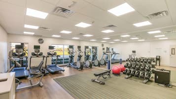 A gym with treadmills, elliptical machines, and free weights.