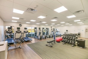 A gym with treadmills, elliptical machines, and free weights.