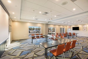 A conference room with a large table, multiple chairs, a projector, and a television screen. - Holiday Inn Express & Suites Jacksonville - Town Center by IHG (Jacksonville)