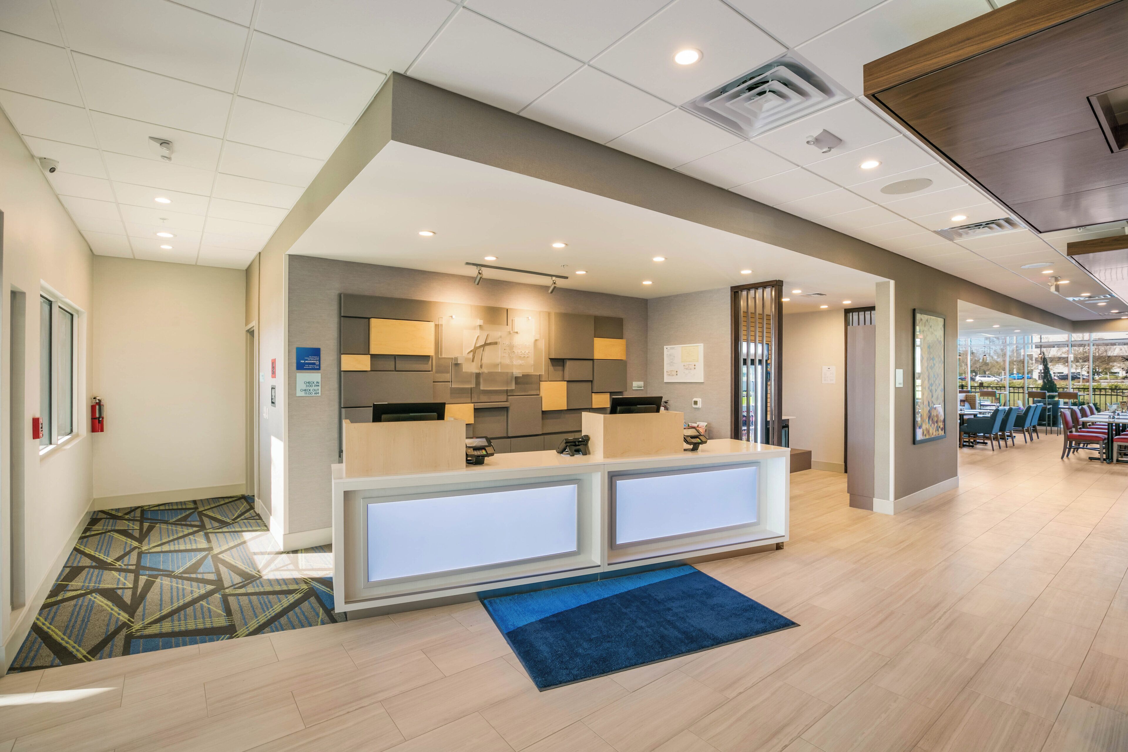A hotel reception area with a modern design, a check-in counter, and a seating area with tables and chairs.