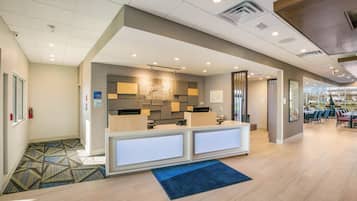 A hotel reception area with a modern design, a check-in counter, and a seating area with tables and chairs.