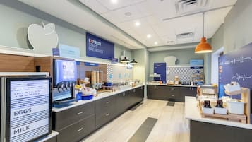 A modern breakfast area with a self-serve station, a bakery section, and a sign indicating the availability of breakfast.