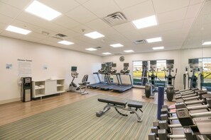 Een fitnessruimte met loopbanden, elliptische trainers en losse gewichten.