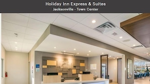 A Holiday Inn Express & Suites lobby with a reception desk, seating area, and a view of the outside.
