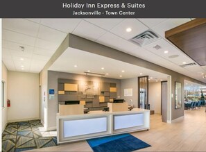 Een Holiday Inn Express & Suites lobby met een receptiebalie, een zithoek en uitzicht naar buiten.