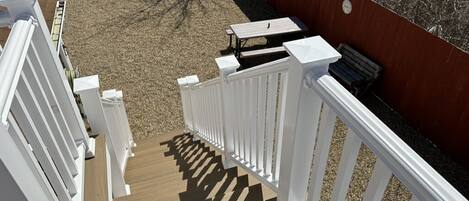 Eine Terrasse mit weißen Geländern, einem Holzboden und einer roten Wand.