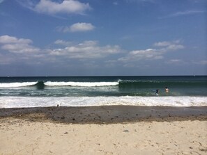A beach with waves, a clear sky, and a few people in the water. - "A COZY PLACE AT FIELDSTONE BEACH" (marshfield)