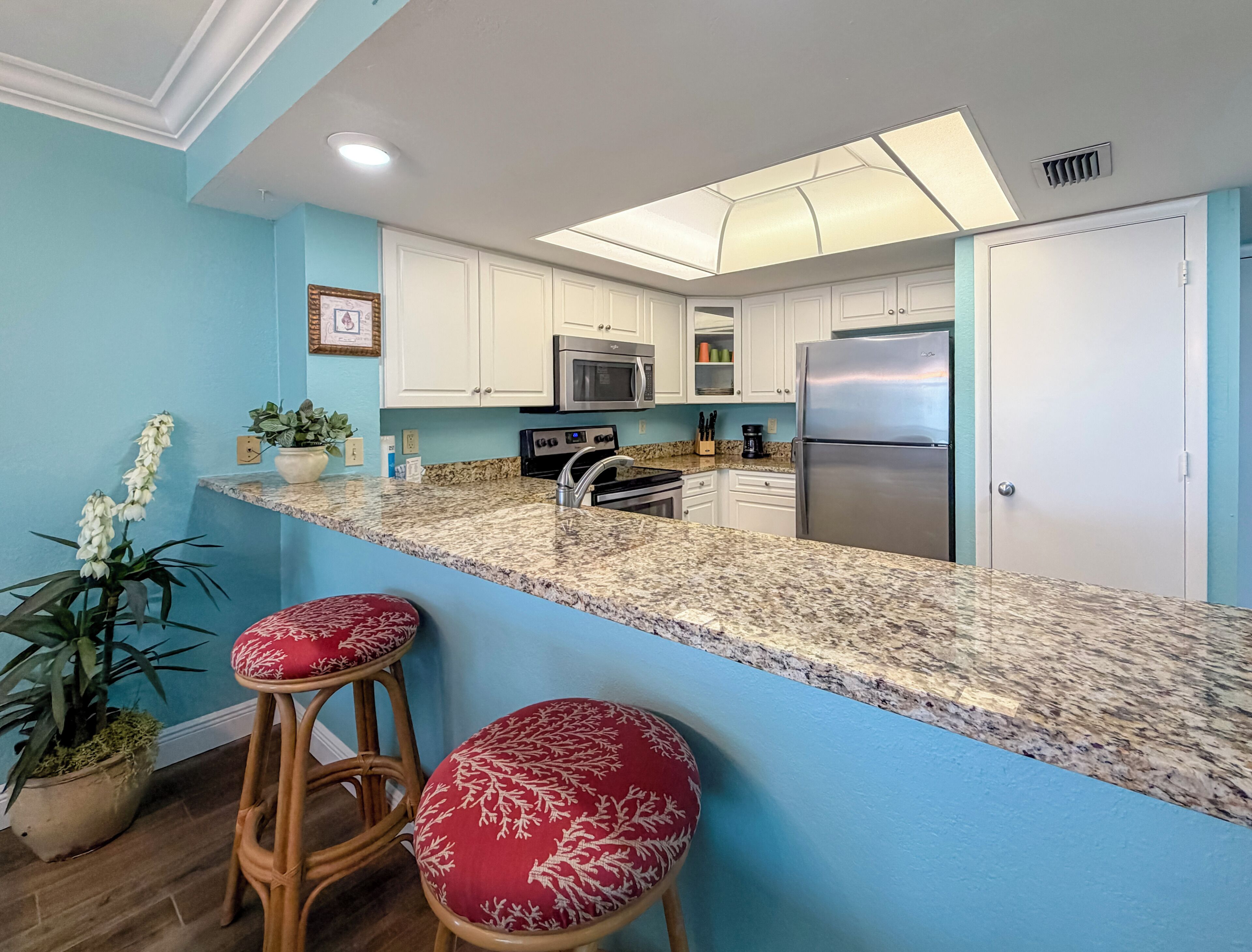 A kitchen with white cabinets, a stainless steel refrigerator, and a granite countertop.
