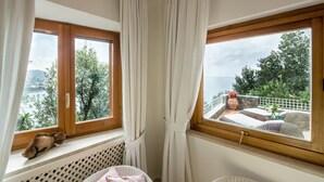 Una habitación con dos ventanas, vistas al mar y muebles de mimbre.