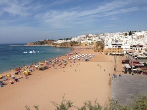A beach with a row of white buildings along the coastline, a sandy beach with umbrellas, and a clear blue sky. - OLD TOWN, Apt. 120m2 in Downtown Albufeira, AIR CONDITIONING / CABLE TV / FREE WIFI (Albufeira)
