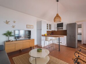 Une cuisine moderne avec des meubles blancs, un réfrigérateur en acier inoxydable et un coin repas comprenant une table ronde et des chaises.