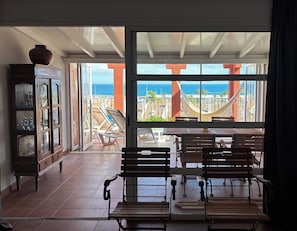 A room with a large sliding glass door leading to an outdoor patio with a view of the ocean.