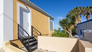 A building with a beige exterior, a white door, and a black staircase leading to a balcony.