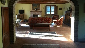 A living room with a fireplace, a sofa, and a television. - Beautiful stone country villa in the hills (Casaprota (Rieti))