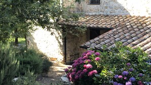 A rustic stone building with a tiled roof, surrounded by lush greenery and vibrant flowers. - Beautiful stone country villa in the hills (Casaprota (Rieti))