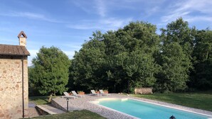 A swimming pool with lounge chairs, surrounded by a stone patio and a stone building. - Beautiful stone country villa in the hills (Casaprota (Rieti))