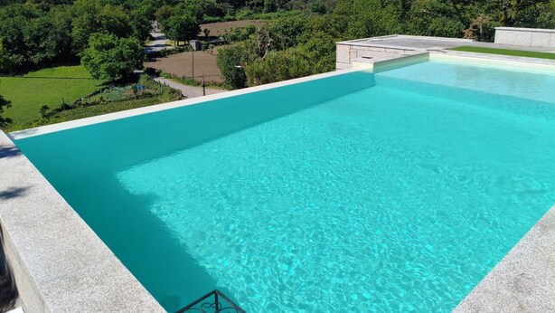A clear blue swimming pool with a view of a lush green landscape and hills in the background. - Nature in its purest state ... (Casais de Vide)