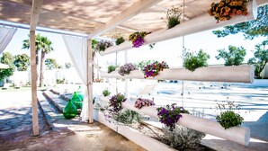 A covered outdoor area with white columns supporting hanging flower planters. - Suite TerraNostra garden with pool in Salento (Ugento)
