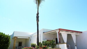 A building with a white exterior, a covered patio area, and a palm tree. - Suite TerraNostra garden with pool in Salento (Ugento)