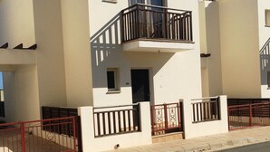 A two-story residential building with a balcony, a small window, and a door.