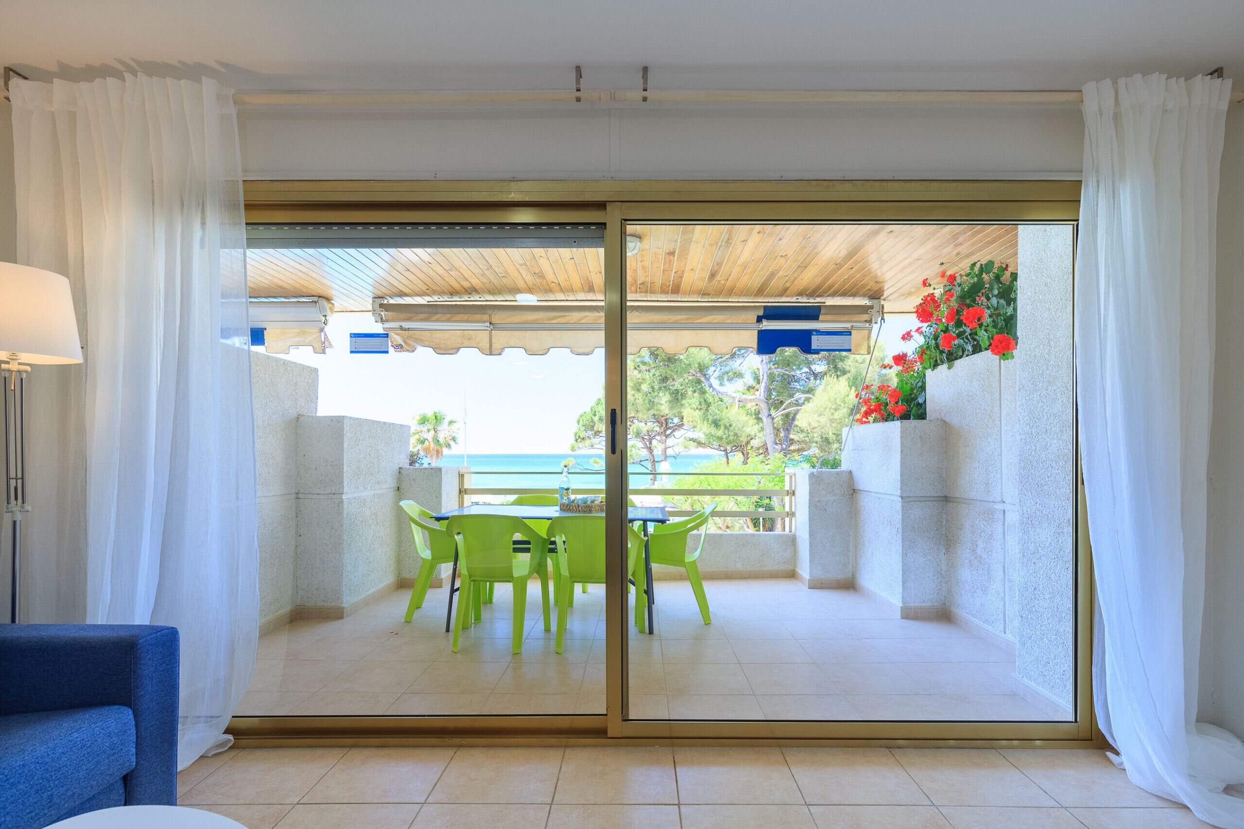 A balcony with a table and chairs, a view of the sea, and a covered area with a wooden ceiling.