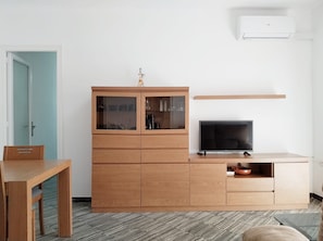 Un salon moderne avec un meuble en bois, un téléviseur à écran plat et un appareil de climatisation.