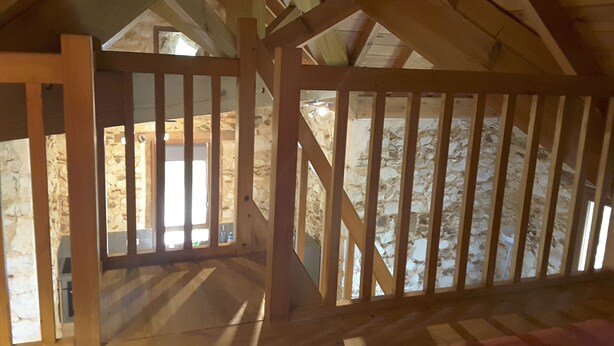 An attic room with a wooden staircase and a stone wall. - Small stone house of the most unusual in the country (Habas)