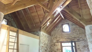A rustic interior with exposed wooden beams, stone walls, and a small window. - Small stone house of the most unusual in the country (Habas)