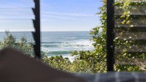 Blick auf den Ozean durch ein Fenster, mit Ausblick auf Strand und Wellen.