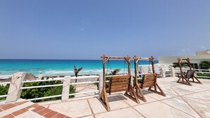 A beachside patio with wooden swing chairs overlooking the ocean. - Cancun Studio Front Beach (Cancún)