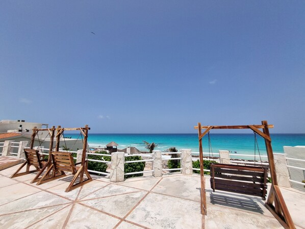 Una terrazza con altalene in legno che si affaccia su una spiaggia.